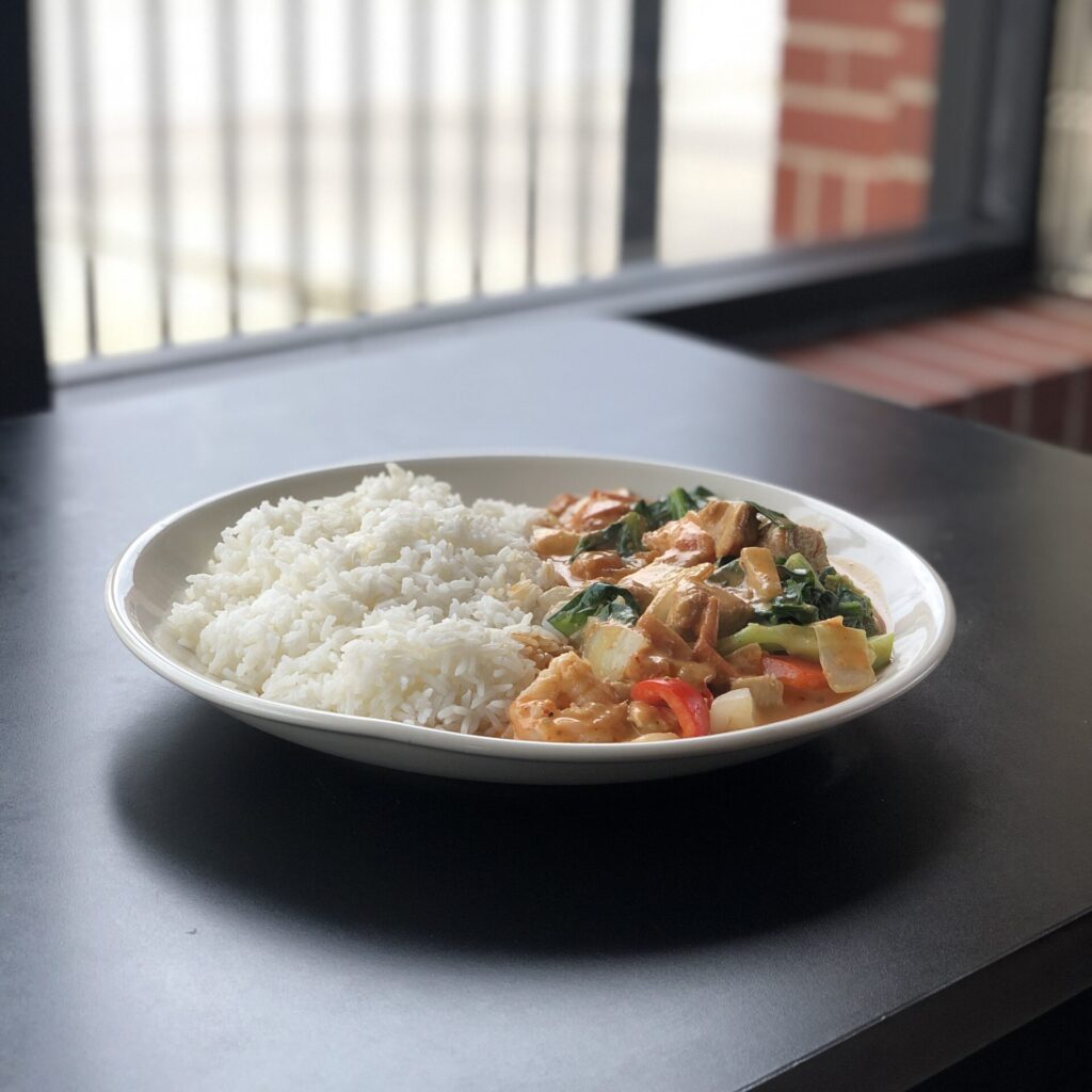 Bowl of Thai panang red curry with chicken, bell peppers, and basil in a creamy coconut curry sauce served with rice.